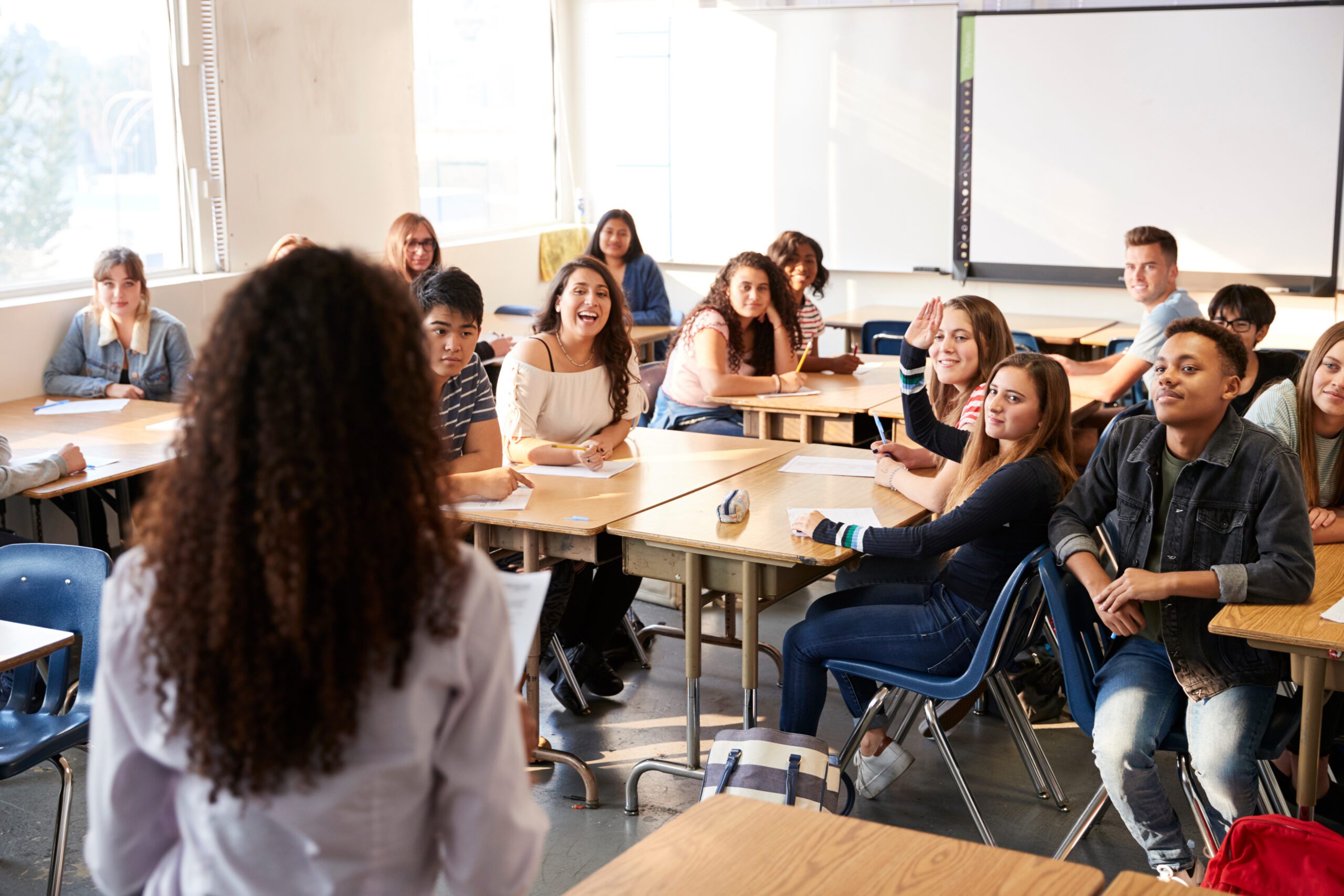 Rear View Of Female High School Teacher Standing At Front Of Class Teaching Lesson Die Herausforderung des Lehrkräftemangels in Deutschland