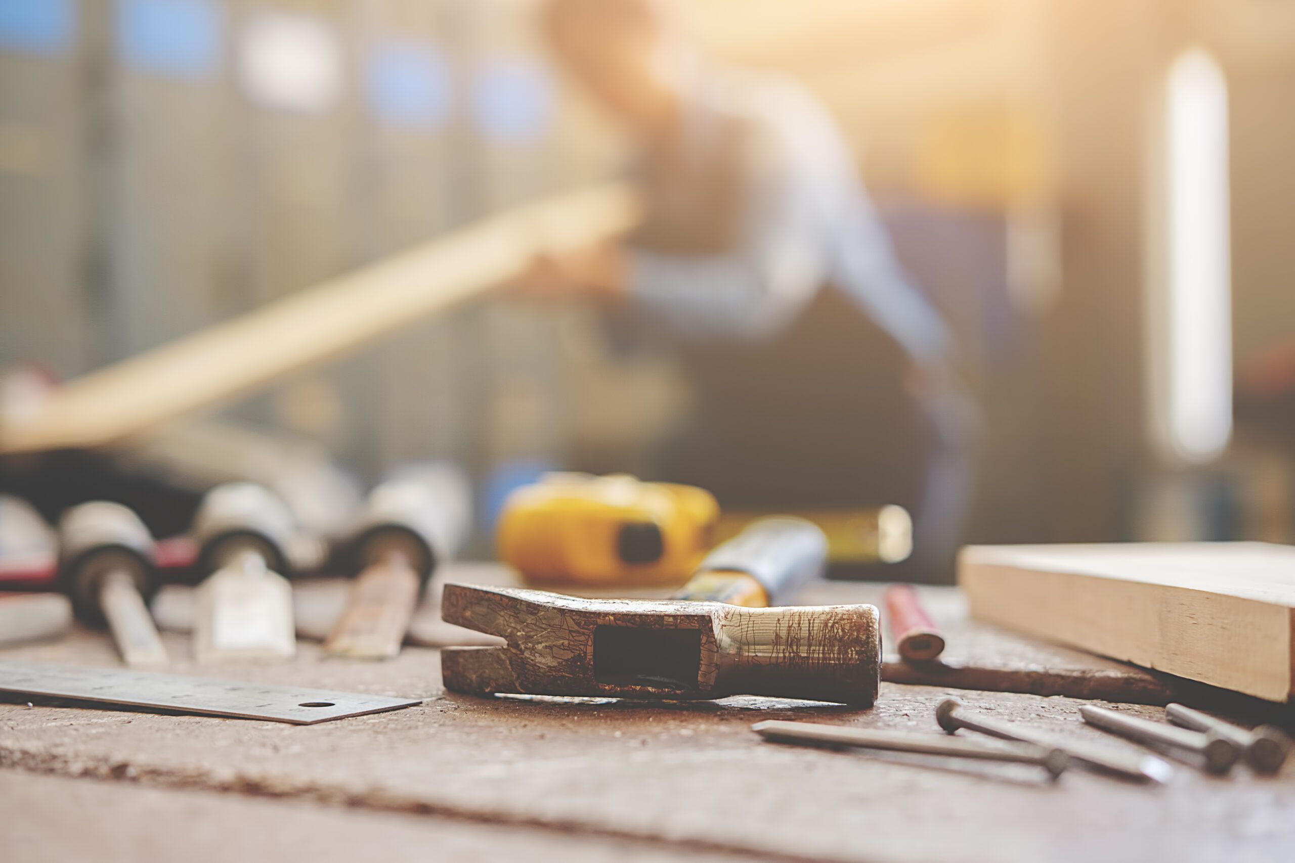 equipment on wooden desk with man working in workshop background Beliebte Ausbildungsplätze 2022