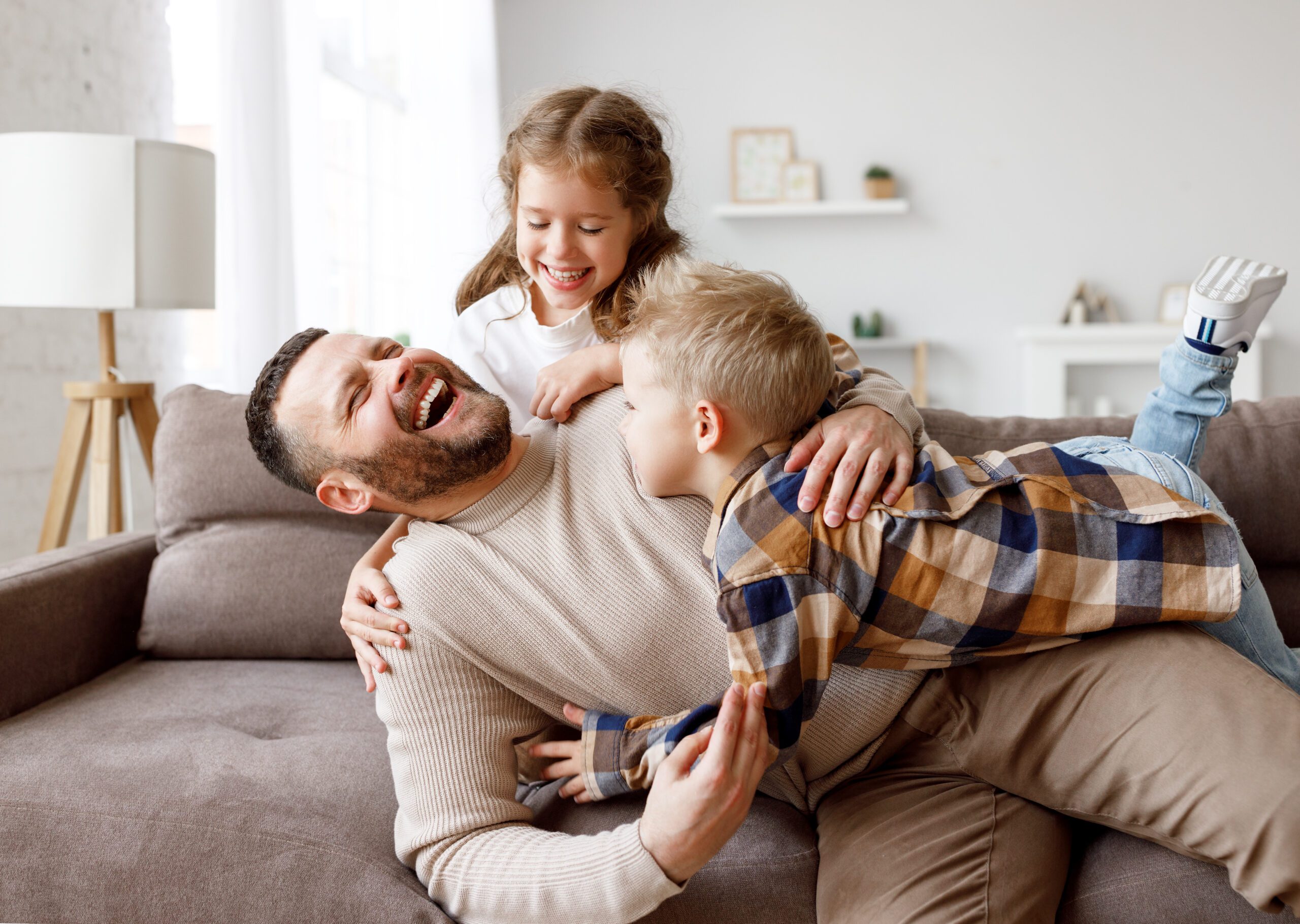 Kids playing with father on sofa Vaterschaft in 2023