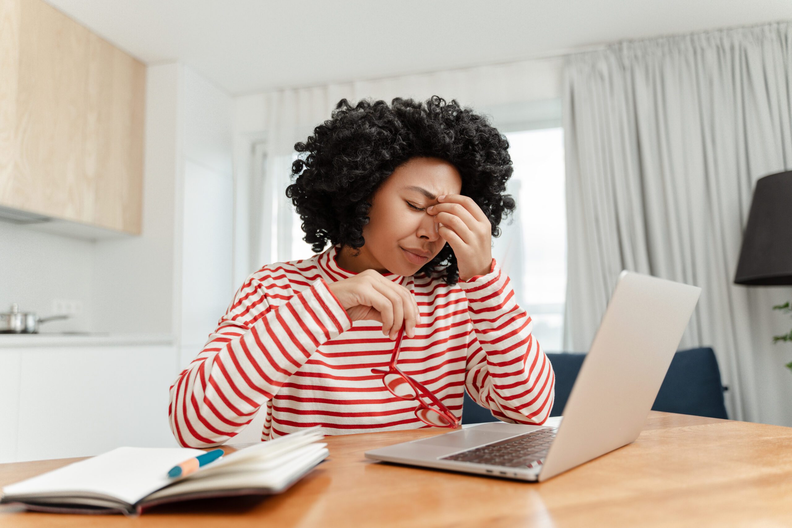 Tired frustrated African American woman using laptop working online from home having eye pain. Unhappy freelancer missed deadline. Headache, stress concept Gesundheitsreport
