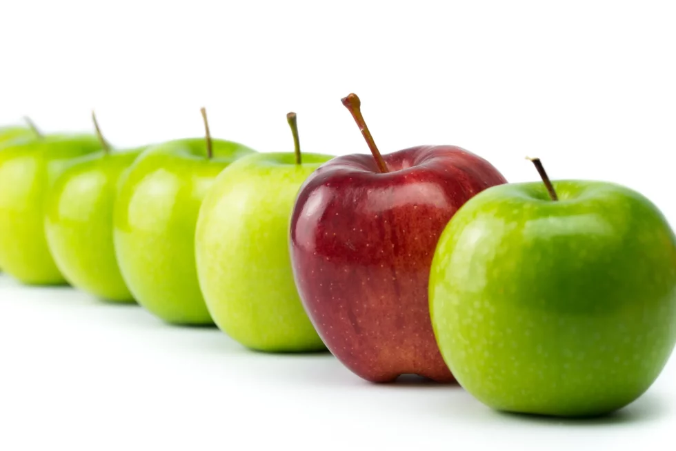 Ein roter Apfel in einer Reihe grüner Äpfel